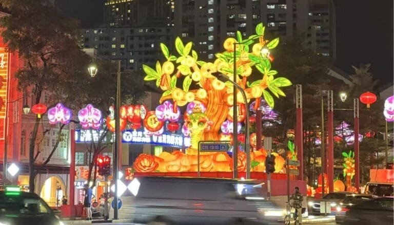 An illuminated snake zodiac display in Singapore Chinatown among traffic, buildings and festival lights.